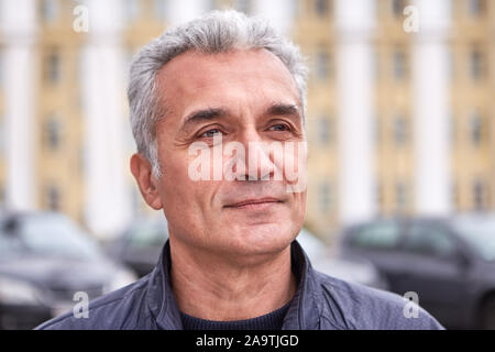 A successful well-groomed man over 50 years, short gray hair, a pleased look, casual clothes, the face of a politician, TV presenter or doctor. Middle Stock Photo