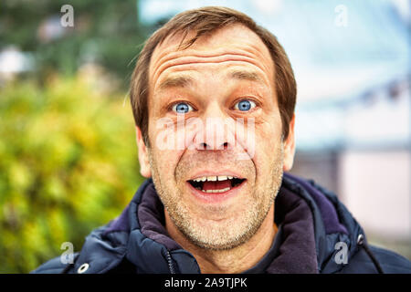 The surprised face of a man of fifty years old against the background of a European street, close-up. Head of a joyful middle-aged male over 50 outdoo Stock Photo