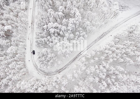 Car on road in winter trough a forest covered with snow. Aerial photography of a road in wintertime trough a forest covered in snow. High mountain pass .