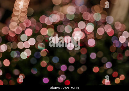 Illuminated abstract round pink, yellow purple and gold bokeh on dark background. Colourful glitter bokeh from out of focus view of decoration bulbs. Stock Photo