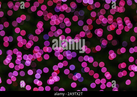 Illuminated Abstract round deep purple bokeh on dark background. Colourful glitter bokeh from out of focus view of decoration bulbs. Stock Photo