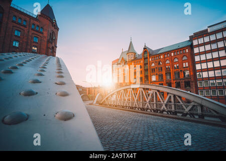 Iron arch bridges in historical warehouses in Speicherstad district in Hamburg, Germany. Backlit sun light flares. Stock Photo