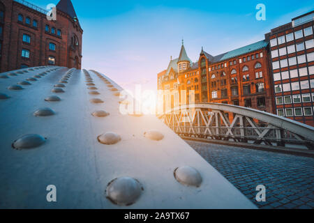 Perspective of iron arch bridges in historical warehouses in Speicherstad district in Hamburg, Germany. Backlit sun light flares. Stock Photo