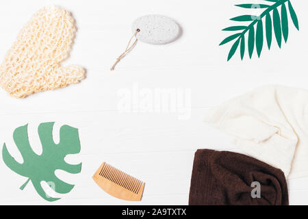 Flat lay composition of items for hygiene and body care, massage glove, pumice stone, wooden hair comb and cotton towels on white table, top view Stock Photo
