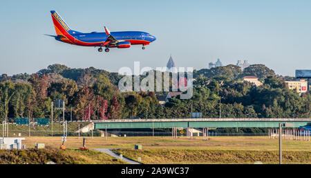 Southwest Airlines jet landing at Hartsfield-Jackson Atlanta International Airport with Downtown Atlanta city skyline visible in the distance. (USA) Stock Photo