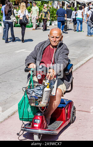 Miami Beach Florida,Ocean Drive,senior seniors citizen citizens,man men male,electric wheelchair scooter,cart,basket,trolley,oxygen,disabled handicapp Stock Photo