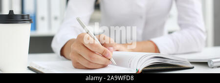 Female hand holding silver pen ready to make note in Stock Photo