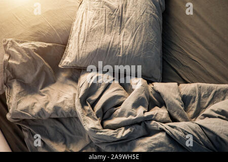 A gray cotton sheet and blankets with pillows on the bed Stock Photo