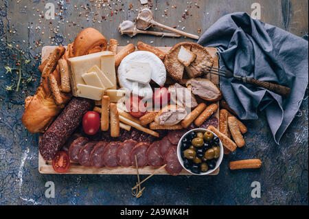 Assorted cheeses, smoked sausages and meat on a cutting board. Mediterranean food. Top view Stock Photo