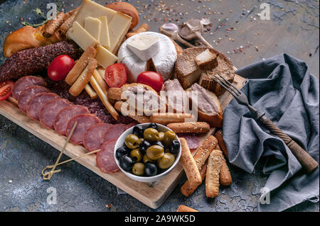 Assorted cheeses, smoked sausages and meat on a cutting board. Mediterranean food. Closeup Stock Photo