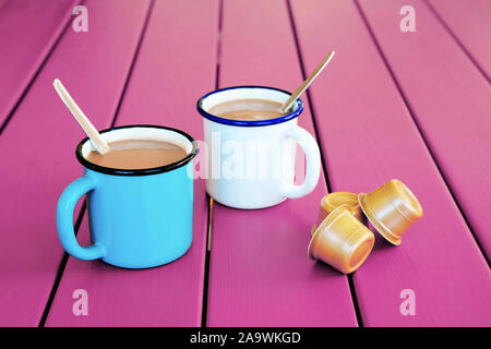 Two vintage coffee cups with espresso capsules on pink wooden table. Morning coffee. Stock Photo