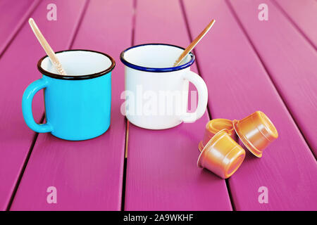 Two vintage coffee cups with espresso capsules on pink wooden table. Morning coffee. Stock Photo