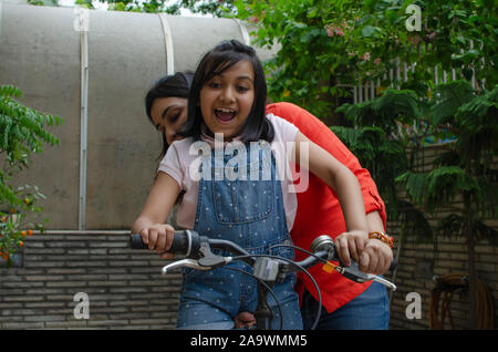 Mother helping daughter riding cycle Stock Photo