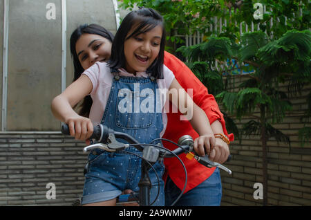 Mother helping daughter riding cycle Stock Photo