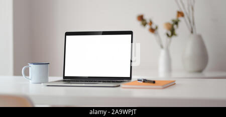 Cropped shot of modern workplace with open laptop computer with office supplies and vase decorations Stock Photo