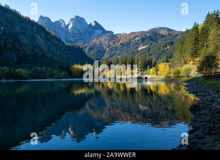 Sunny idyllic colorful autumn alpine view. Peaceful mountain lake with clear transparent water and reflections. Gosauseen or Vorderer Gosausee lake, Stock Photo