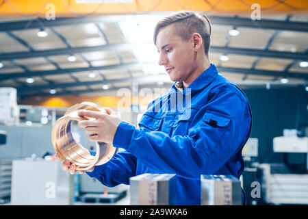 Apprentice in metalworking looking at workpiece Stock Photo