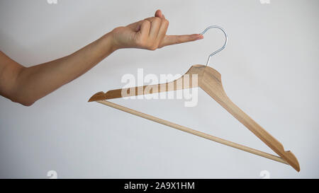 Wooden clothes hanger hanging from a female hand. Stock Photo