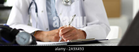 Hands of female GP making notes with silver pen Stock Photo