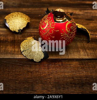 Broken Christmas ball with glass shards on wooden table Stock Photo