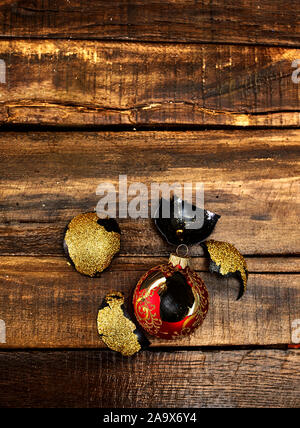 Broken Xmas ball with glass shards on wooden table Stock Photo