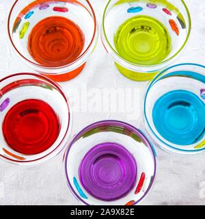 Colorful drinking glasses on white background. Round circuls red, orange, blue green purple neon lights. Stock Photo