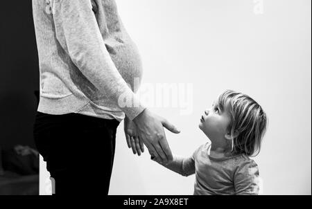 Pregnant mother with two year old daughter and baby bump  Photograph taken by Simon Dack Stock Photo