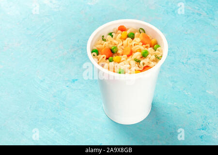 Ramen cup, instant soba noodles in a plastic cup with vegetables and a place for text Stock Photo