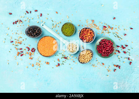 Legumes, shot from above on a blue background with a place for text. Vibrant pulses including colorful beans, lentils, chickpeas, a flatlay composition Stock Photo