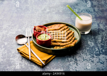 Aloo Paratha / Indian Potato stuffed Flatbread with butter on top. Served with fresh sweet Lassi, chutney and pickle . selective focus Stock Photo