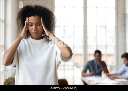 African ethnic company employee feeling strong headache. Stock Photo