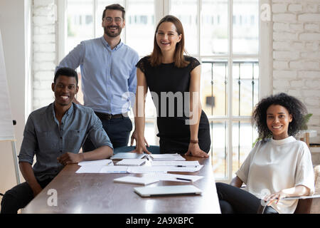 Joyful millennial diverse professionals gathered near table. Stock Photo
