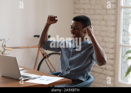 Overjoyed mixed race businessman celebrating corporate success. Stock Photo