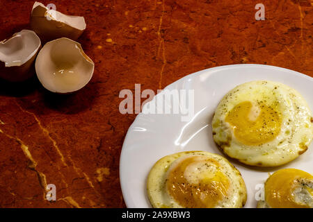 Three fried eggs on a plate and shells from them Stock Photo