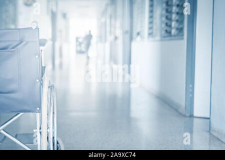 Empty wheelchair parked in hospital pathway blurred with patient walk in hospital Stock Photo