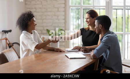 Happy mixed race young hr managers shaking hands with applicant. Stock Photo