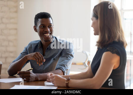 Laughing young african american male employee joking with female colleague. Stock Photo
