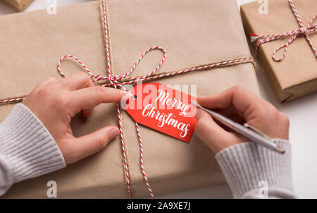 Woman writing Merry Christmas text on red label Stock Photo