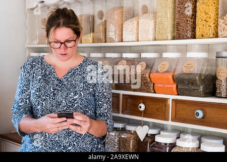 Woman standing in kitchen, using mobile phone. Stock Photo