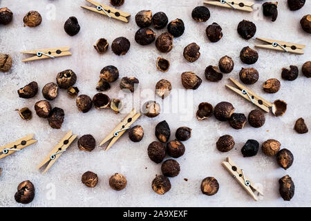 High angle close up of wooden clothes pegs and dried brown soap nuts. Stock Photo