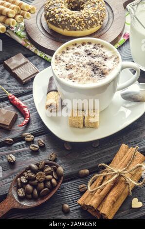 Elegant concept of serving coffee in vintage style. Coffee with foam and cinnamon with various sweets and decoration. Stock Photo