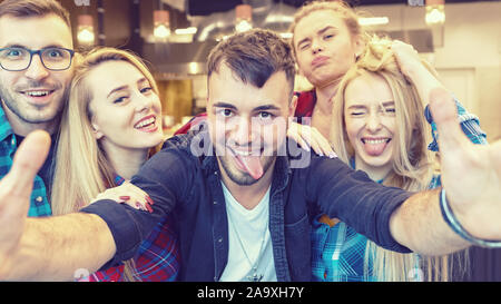 Millennial international friends taking selfie with funny faces at party Stock Photo