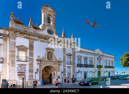 Passenger jet flying over Faro landmark, Arco da Vila coming into land at Faro airport, Faro, Algarve, Portugal.