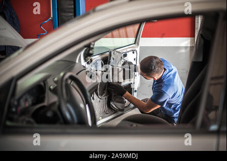 Car master mechanic works on the interior of a car door at vehicle service workshop Stock Photo