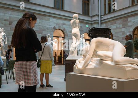 Woman art, view of a young woman looking at a 19th century sculpture titled In Sorrow (1852) by Johan Teodor Lundberg in the Nationalmuseum, Stockholm Stock Photo
