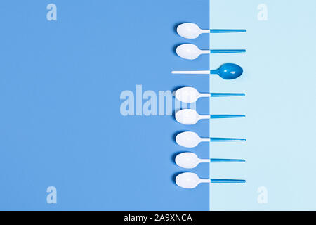 Beautiful and dangerous plastic spoons on two-toned blue background. Flat lay, top view, copy space. Stock Photo