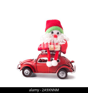 Toy Santa delivering presents with retro car Volkswagen Beetle, white background Stock Photo