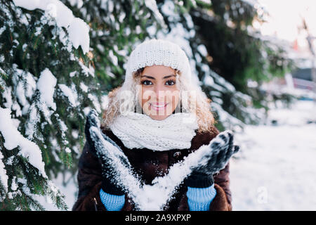 Happy young afro american woman blowing snow in winter park Stock Photo