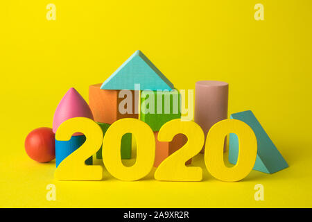 Creative background made of wooden 2020 numbers and colorful geometric shapes on yellow minimal new year concept. Stock Photo
