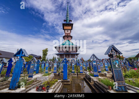 Graves and Birth of Virgin Mary church on Cimitirul Vesel - Merry Cemetery, famous cemetery in the village of Sapanta in Maramures county, Romania Stock Photo